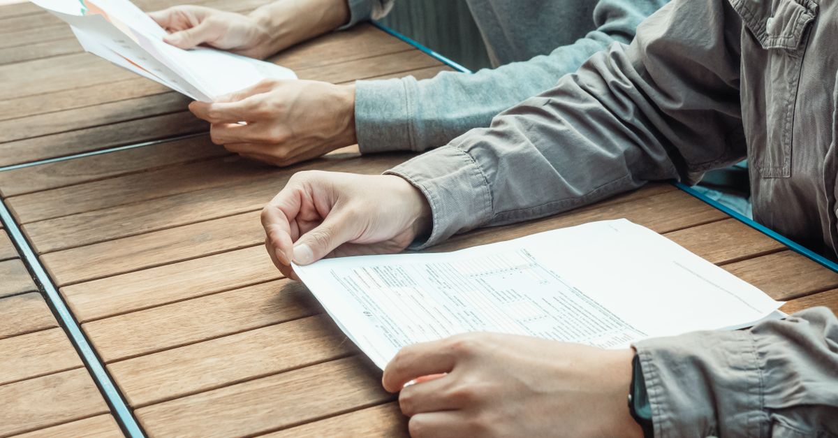 Persona revisando planillas de pagos y recibos en una mesa de trabajo