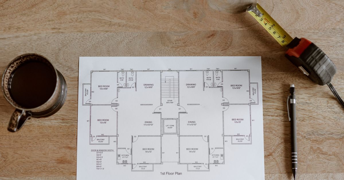 Plano de un departamento extendido sobre una mesa junto a una carpeta con documentos